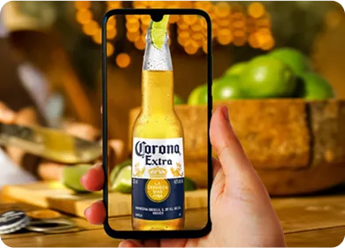 Uma mão segurando um celular com a imagem de um garrafa de corona.